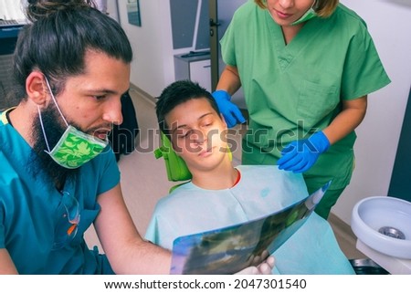 Male and female dentists showing a young boy patient his teeth x-ray image in the dental office.