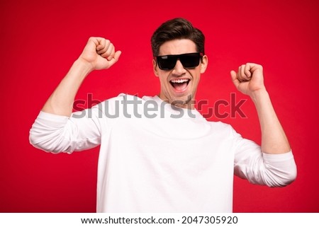 Photo of funky brunet young guy hands fists yell wear white shirt spectacles isolated on red color background
