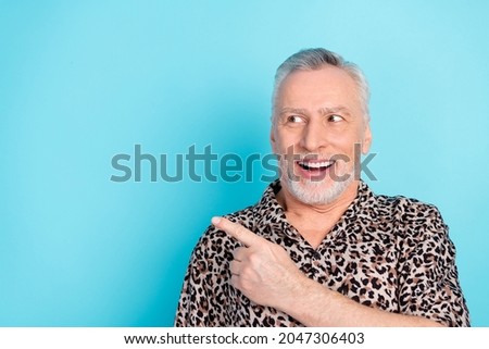 Photo of funky grey hairdo senior man point look empty space wear leopard shirt isolated on bright blue color background