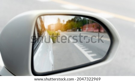 Abstract and blurred of wing mirror of white car on the road heading towards the goal of the trip. There is a traffic line on the road.