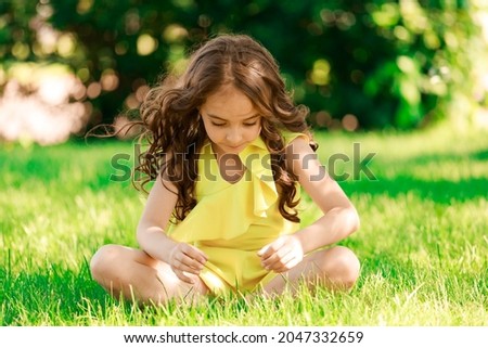 young brunette girl sitting on the grass in the park. High quality photo