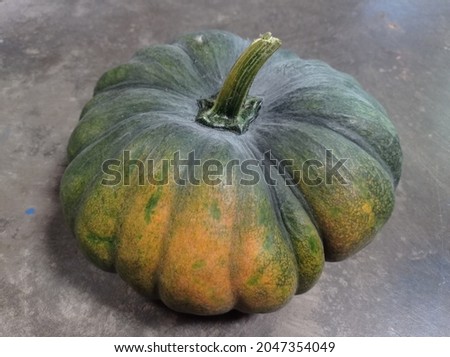 Green pumpkin with all its of benefits isolated on a dull black background.