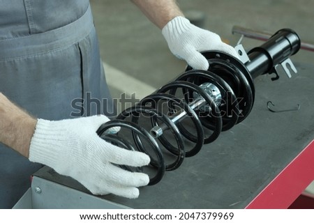 Spare parts of the car suspension.The car mechanic checks the compatibility of the shock absorber strut and the spring.Vehicle maintenance at a car service station. Royalty-Free Stock Photo #2047379969