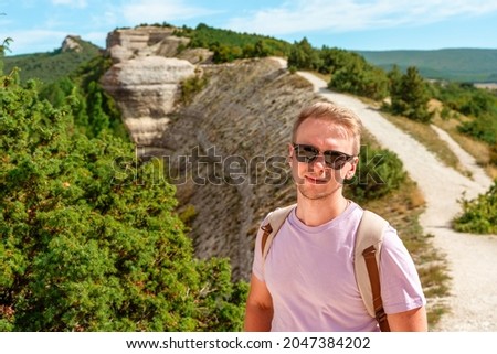 A young man on a mountain hill with a beautiful sky in the Crimea, the concept of a healthy lifestyle
