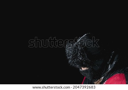 A young guy is wrapped up in winter clothes at night