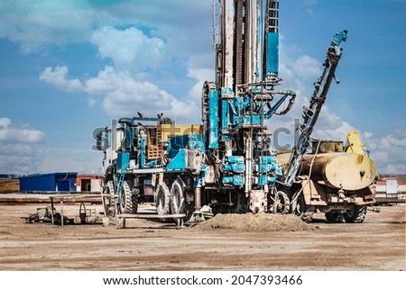 The drilling rig close-up is drilling a well against the background of the cloudy sky. Deep hole drilling. Geological exploration work. Mineral exploration. Powerful drill drills a well