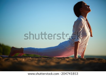 Photo of active and fit girl doing stretching exercise on sandy beach