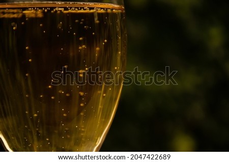 Glass of beer on green blurred background. Bubbles rise in beverage. Alcohol consumption concept. Golden bubbles background water.