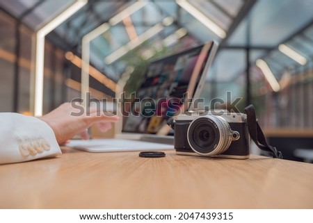A freelance photographer works remotely, a thin mobile computer with a photo on the screen and a camera in the foreground. Creative work, retouching or creating designs.