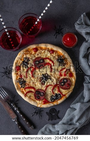 Halloween funny pizza with spiders, Creative idea for Halloween pizza on dark gray background with drinks and decorations