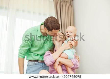 Couple kissing white holding their baby (focus on the eyes of baby)