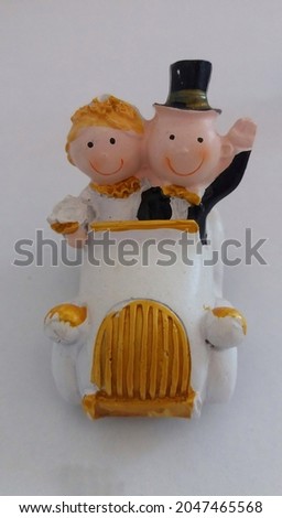 bride and groom sitting on the car and greeting people on they wedding day black and white trinket