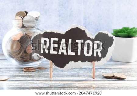 Cubes form the word realtor in front of a miniature house.
