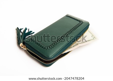 green women's wallet with a zipper with money on a white background.