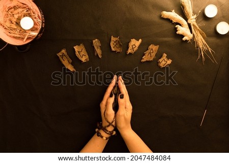 oracle or wooden rune reading with woman hands on black background