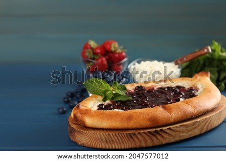 Delicious sweet cottage cheese pastry with cherry jam on blue wooden table, closeup. Space for text