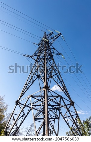 A Rusty power line is on the blue sky background. Vertical