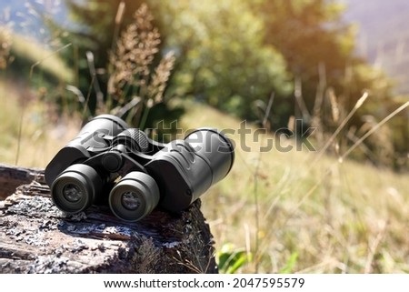 Modern binoculars on wooden surface outdoors, space for text