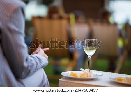Girl drinking wine at the event. A glass of wine is on the table, the background is blurred.