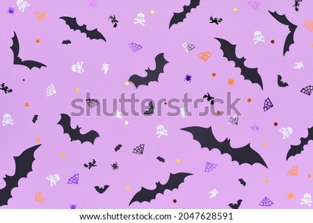 Happy Halloween concept. Halloween backdrop made of different bats on a purple background. Decorated with pinata confetti in the shape of skulls, spiders, spider webs, bats, witches and ghosts.