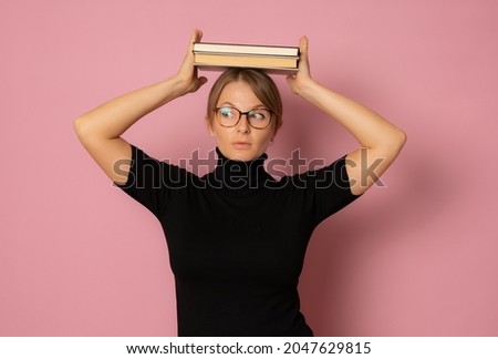 Photo of young beautiful pensive woman in glasses with books isolated on pink color background