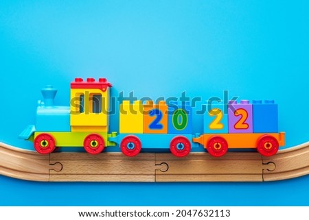 Happy New year 2022. Christmas toy locomotive with numbers 2022 on a blue background. Copyspace.