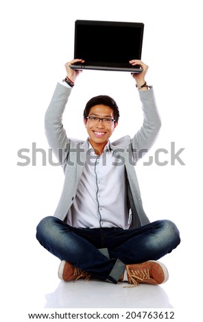 Happy asian man sitting on the floor and holding laptop 