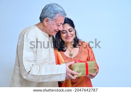 Senior man with daughter in Tradional clothes on the occasion of festivities holding gift box in hand Royalty-Free Stock Photo #2047642787