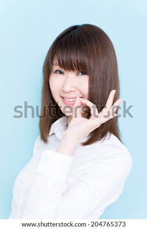 young business woman showing OK sign against blue background 