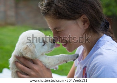 This is called love. 
A girl is playing with a newborn labrador puppy in the backyard
