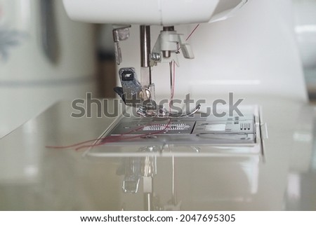 White sewing machine with red thread.