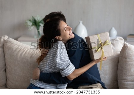 Happy young 30s latina woman embracing loving husband, feeling thankful for getting present in wrapped gift box, celebrating happy birthday or marriage anniversary, international women s day. Royalty-Free Stock Photo #2047731335