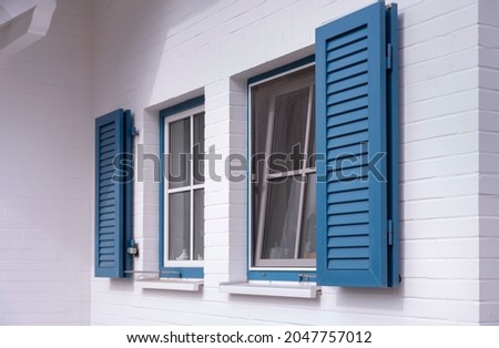 blue louvered window shutters on a white house Royalty-Free Stock Photo #2047757012