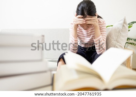 Anxious teenage girl has tension during exam preparation,Stressed worried asian student while studying reading a textbook before final test at her home,afraid of failing the exam,education concept Royalty-Free Stock Photo #2047761935