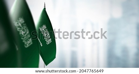 Small flags of Saudi Arabia on a blurry background of the city
