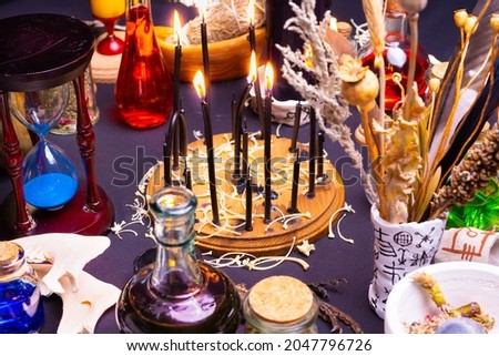 Witchcraft still life with black burning candles selective focus. Esoteric gothic and occult witch table for Halloween. Various magic objects and ritual arrangement. Gothic Halloween. 