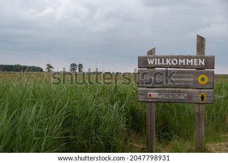 A sign with the inscription "Welcome National Park Vorpommersche Boddenlandschaft" in front of the landscape on the Fischland-Darß-Zingst peninsula