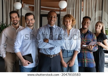 Portrait of happy confident African American business leader and millennial diverse team. Middle aged mentor, coach, teacher with multiethnic group of young interns smiling at camera. Head shot