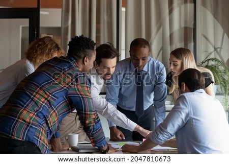 Busy diverse business team working on project together, talking, planning tasks. Employees meeting at conference table, talking, sticking notes, discussing documents. Teamwork, scrum management Royalty-Free Stock Photo #2047810673