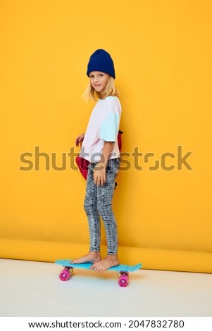 schoolgirl rides a skateboard with a red backpack isolated background