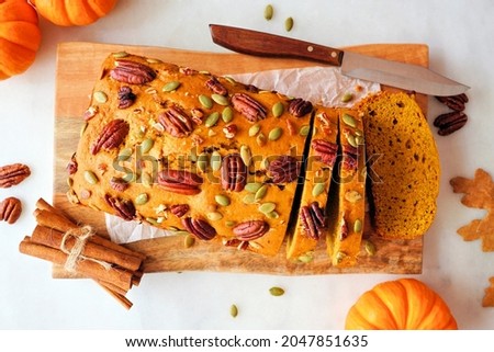 Fall pumpkin bread sliced. Overhead view table scene on a white marble background.