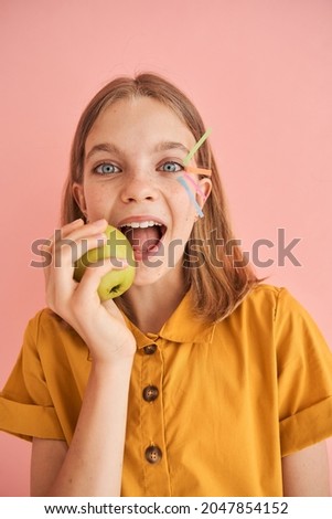 Little girl with stickers on her face eating apple