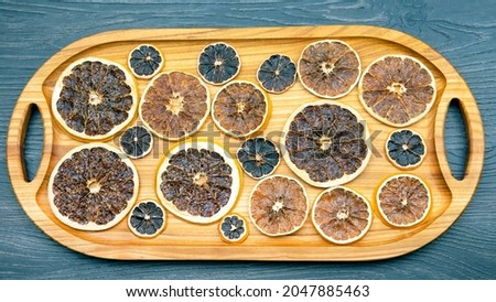 dried citrus fruit pieces are laid out on a wooden board for product transfer. vitamin food
