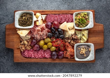 Plateau snack for wine. Prosciutto, smoked sausage, olives, cheese, pates. Food for a large company. Ready menu for the restaurant. Neutral gray blue textured background