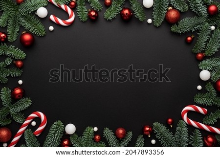 Black background with Christmas decorations made of fir branches, candy cane and Christmas balls