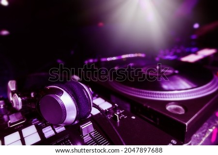 Electronic dj equipment at nightclub, mixer, headphones and turntable with record, colored image with copyspace