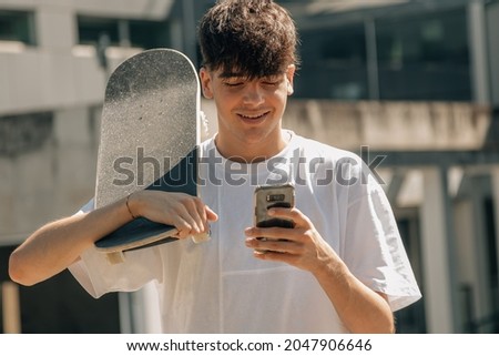 teenager with mobile phone and skateboard on the street