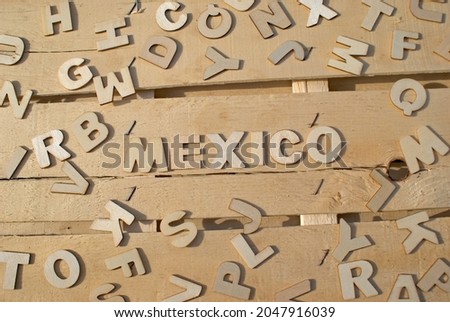 Word Mexico made of wooden block letters on the background of other letters above the composition of the surface of the wooden board