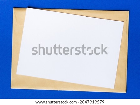 blank sheet of paper and craft envelope on blue background
