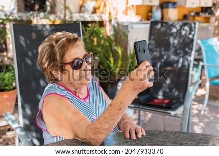old woman with sunglasses taking a selfie on a sunny day in the garden